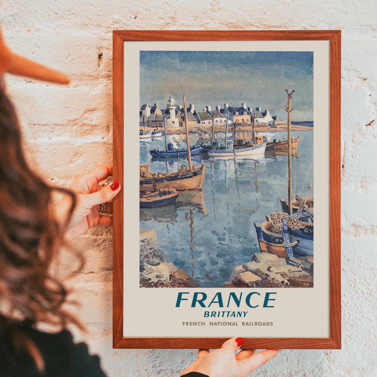 France Brittany Railway poster by Edmond Ceria featuring blue harbor boats, pale village roofs, cream sky, and coastal scenery, with wooden magnetic frame on white background