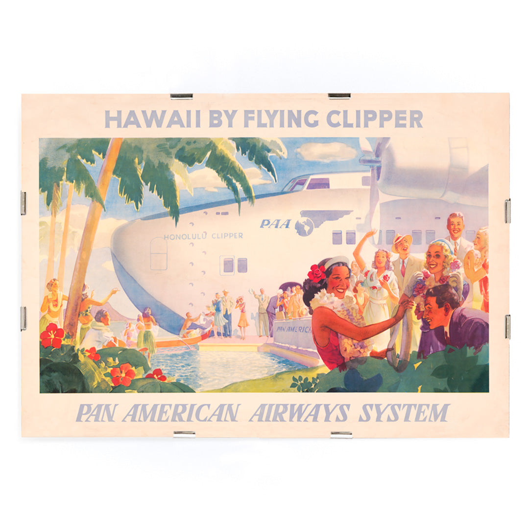 Vintage travel poster of Pan American Airways seaplane in Hawaii with people greeting each other with leis and Hawaiian welcome scene, framed and displayed in modern living room decor
