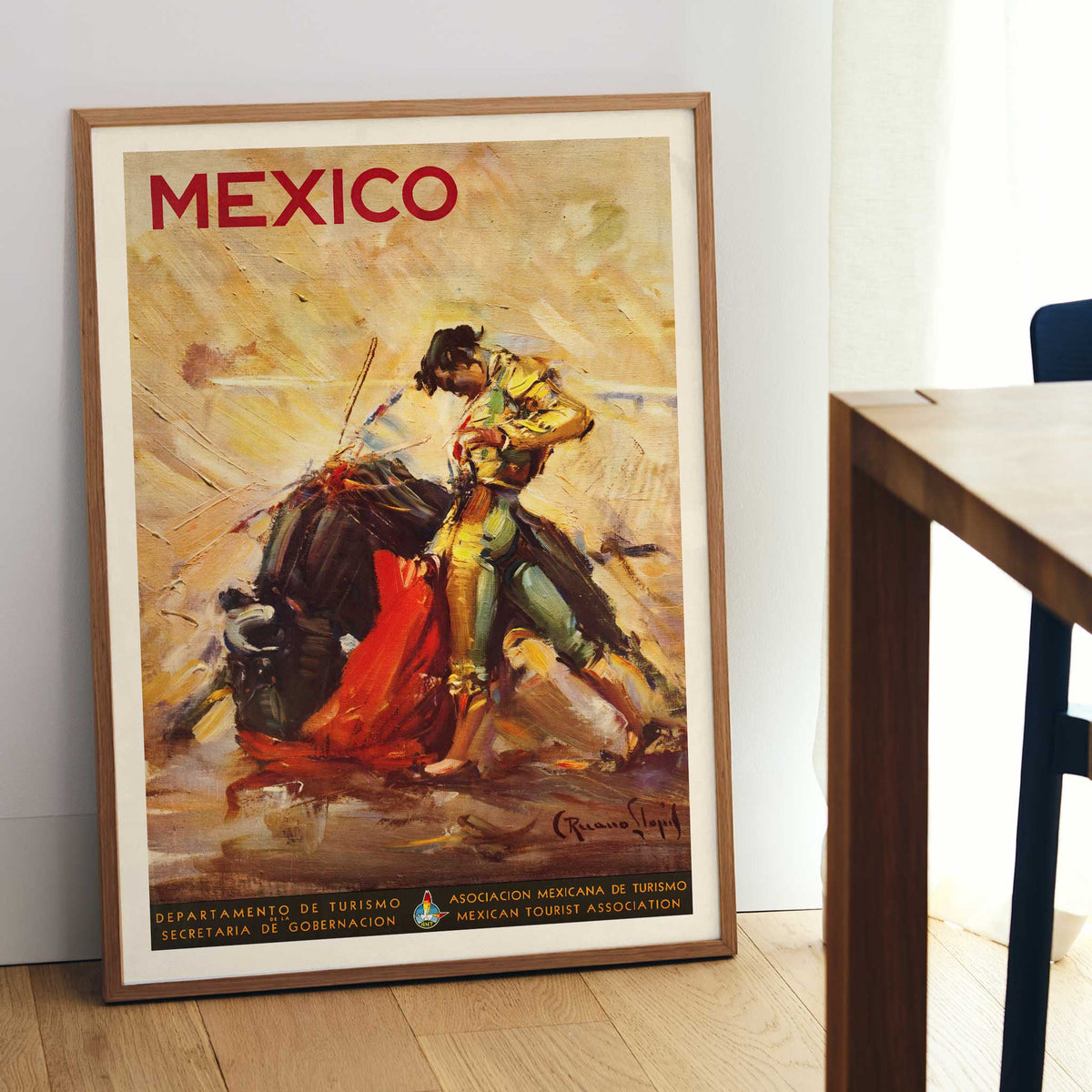 Mexico travel poster by Carlos Ruano Llopis showing a matador facing a bull in a dramatic vintage tourism scene, with wooden magnetic frame on white background
