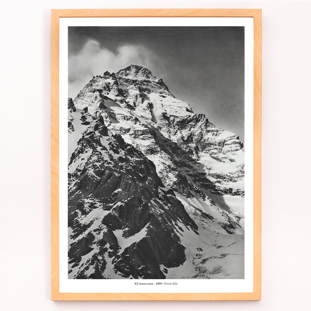 Black and white photograph and poster of K2 west face by Vittorio Sella showing the snow-covered mountain peak, framed and displayed in modern living room decor