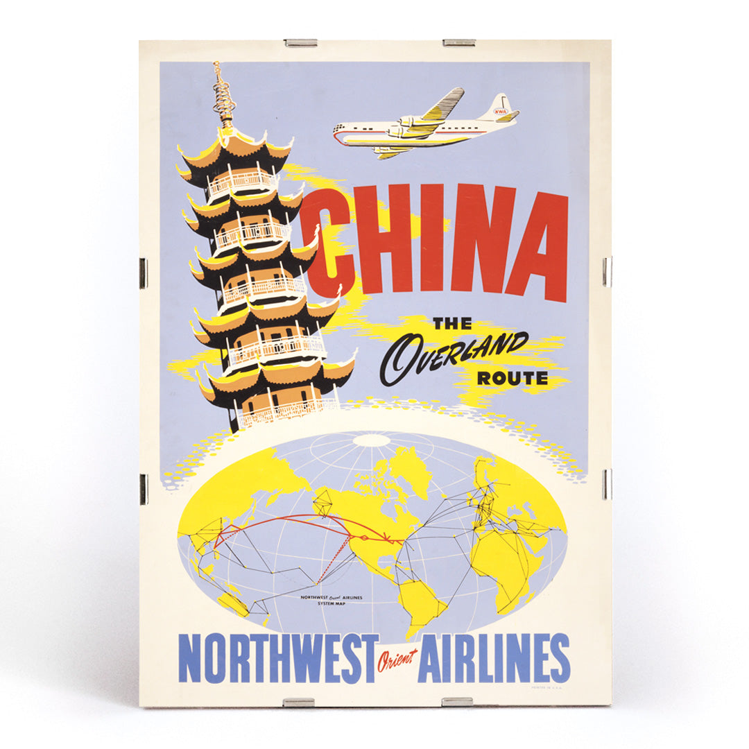 Vintage travel poster of China featuring a pagoda airplane and world map promoting the overland route by Northwest Orient Airlines, framed and displayed in modern living room decor