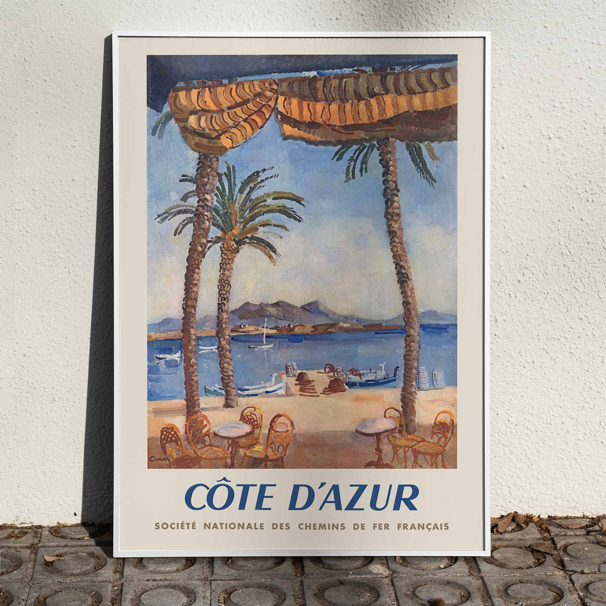 Edmond Céria French Riviera Railway poster with palm trees, blue sea, sandy beach, ochre canopies, vintage travel style, framed and displayed in home decor
