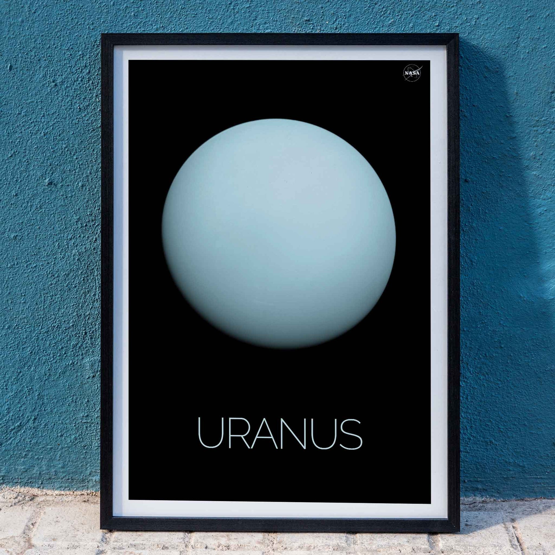 NASA poster of the planet Uranus featuring a light blue sphere against a black background with the title Uranus, framed and displayed in home decor