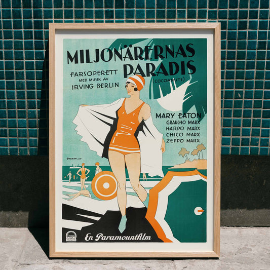 Vintage poster of Miljonärernas Paradis with beach scene and swimmers illustrated by Eric Rohman for The Cocoanuts, framed and displayed in home decor