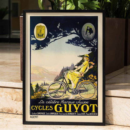 Woman in yellow riding a bicycle through a scenic landscape Cycles Guyot vintage poster artwork, framed and displayed in home decor