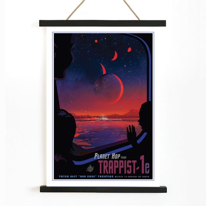 Colorful sci fi poster of TRAPPIST-1e by NASA showing vibrant alien landscape with planets glowing sky and silhouetted figures viewed from a window, with wooden magnetic frame on white background